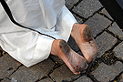 Pies descalzos de un penitente con cruz de la Hermandad del Transporte