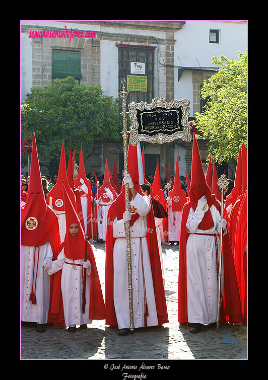 Nazareno portando el Banderín conmemorativo del XXV aniversario de la reorganización de la Hermandad de la Sagrada Cena