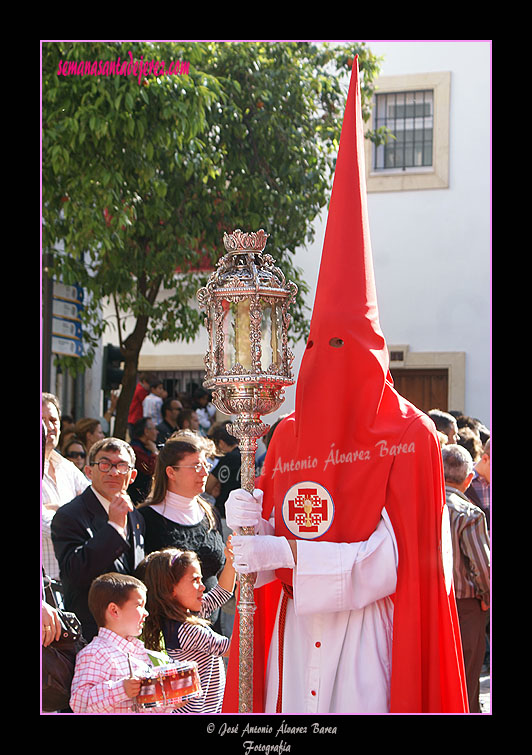 Nazareno portando un cirial de respeto que acompaña a la Bandera de la Virgen de la Hermandad de la Sagrada Cena