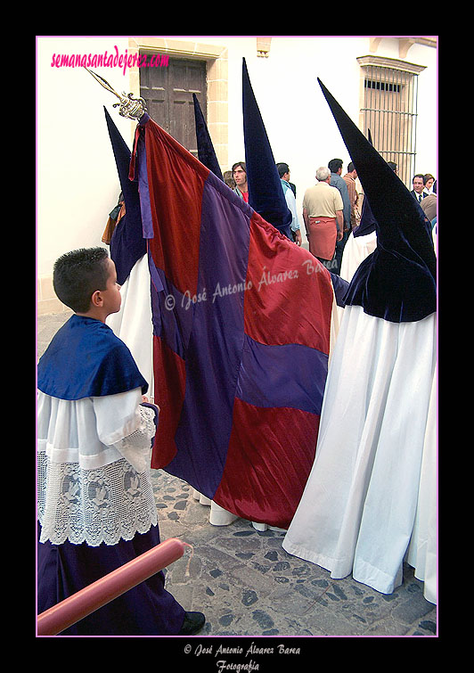 Nazareno portando la Bandera del Señor de la Hermandad de la Candelaria
