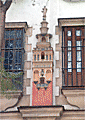 La Giralda, en alto relieve, flanqueada de dos jarras con azucenas sobre el dintel de la puerta principal de la Escuela de San José
