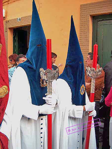 Nazarenos con portahachones de velas rojas acompañan al Banderín Eucarístico de la Hermandad de la Amargura
