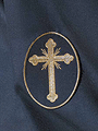 Escudo sobre el antifaz de nazareno de la Hermandad de la Redención