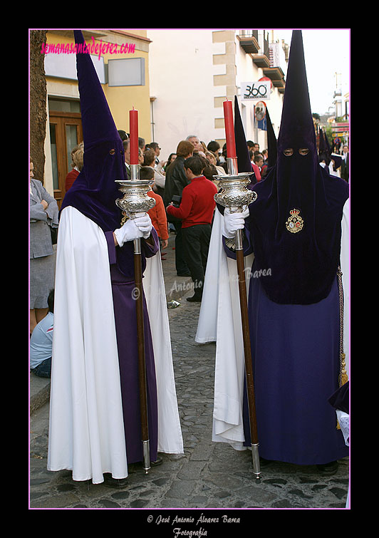 Nazarenos con portavelas acompañando al Estandarte Sacramental de la Hermandad de la Candelaria