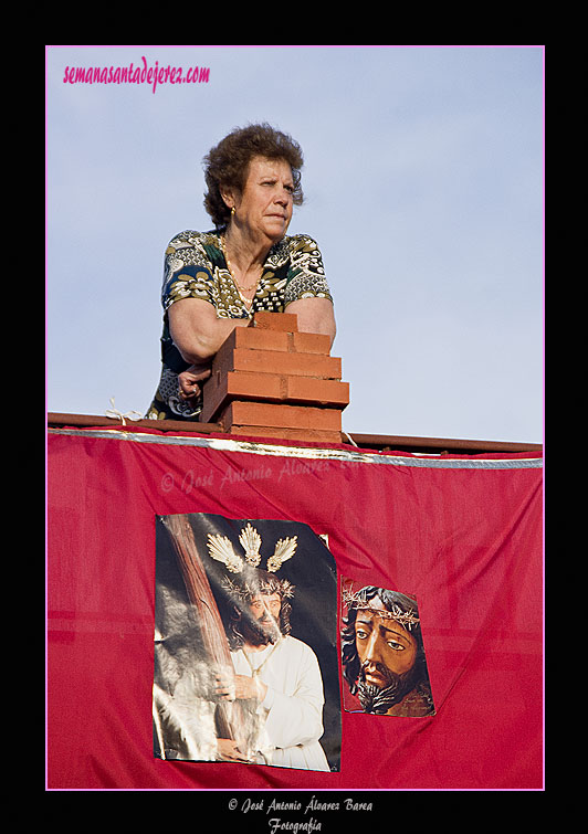 Vecina observando el paso de la Agrupación Parroquial de Nuestro Padre Jesús de la Salud