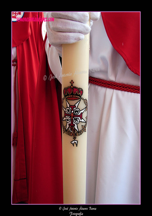 Cirios de los últimos tramos de nazarenos con escudo pintado a mano del cortejo de la Hermandad de la Sagrada Cena
