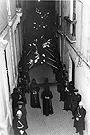 El 7 de abril de 1941 la Hermandad del Amor y Sacrificio hacía su primera Estación de Penitencia. En este momento el cortejo está en la calle Francos, casi a punto de recogerse en la Iglesia-Residencia de los Jesuitas que estuvo en la Plaza de la Compañía. Los penitentes en los primeros años no portaban cirios sino hachones.(Foto: Manuel Pereiras)