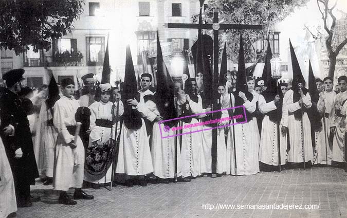 La Hermandad del Mayor Dolor está terminando la Estación de Penitencia: el cortejo del Señor está a las puertas del Templo del Patrón de la Ciudad. La foto es posterior a 1952, pues en este año se colocó el azulejo de la Virgen en la plaza-compás de la Iglesia Parroquial (Foto: Manuel Pereiras Hurtado)