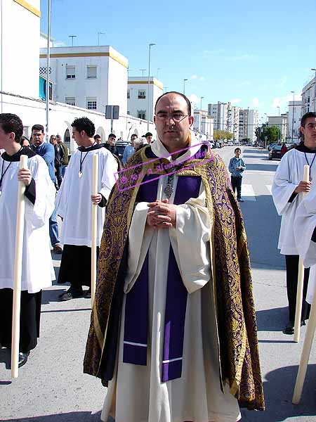 Preste acompañado de acólitos detras del paso de María Santísima del Consuelo